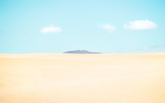 Desert landscape with a mountain between the dunes on sunny day.