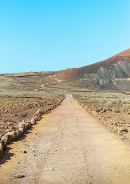 Desert landscape with a patch between the mountains on sunny day. Way to Calder&oacute;n Hondo volcano in Fuerteventura.
