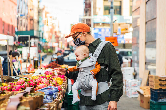 Father with baby girl buying pitayas on street in city during COVID-19 crisis