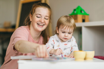 Mom draws with a one-year-old baby. Development, creativity and education of children at home