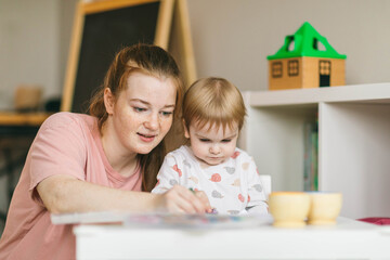 Mom draws with a one-year-old baby. Development, creativity and education of children at home