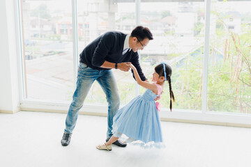 An Asian father and daughter are dancing, dad teaches daughters to dance in a fun room