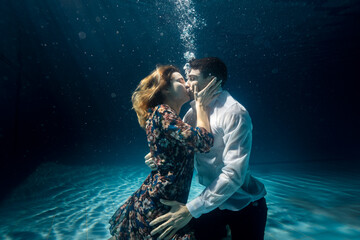 Cinematic shot of young carefree romantic loving couple is kissing with passion in blu underwater...