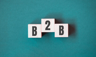 Concept word B2B - business to business on cubes on a beautiful green background. Business concept. Copy space.