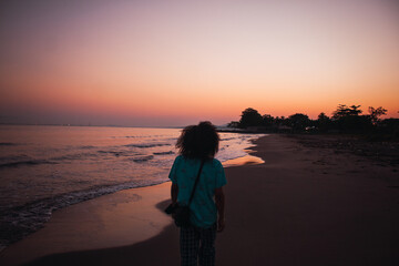 Hombre de cabello largo caminando en la playa al amanecer