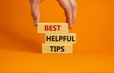 Best helpful tips symbol. Wooden blocks with words 'Best helpful tips'. Beautiful orange background. Businessman hand. Business, Best helpful tips concept. Copy space.