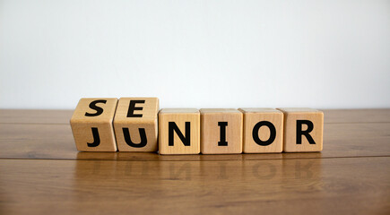 From junior to senior symbol. Turned cubes and changed the word 'junior' to 'senior'. Beautiful wooden table, white background, copy space. Business and junior or senior concept. - obrazy, fototapety, plakaty