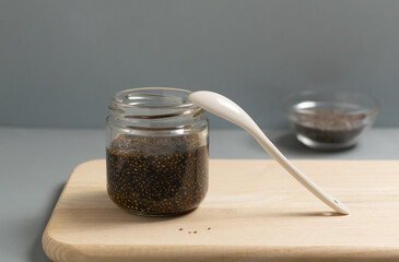 A glass jar of chia seeds with soy sauce and nori seaweed on a gray background. Vegetarian black caviar. Superfood. Copy space.