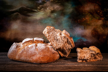 Country bread with floured crust with pieces on a barn wood board
