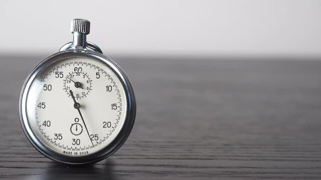 A stopwatch on a dark wooden table. A tool for measuring time. Macrophotographs. Old vintage stopwatch, the hand is moving. Copy space space.