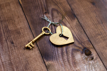 Top view shot of gold heart and key on wood background with copy space