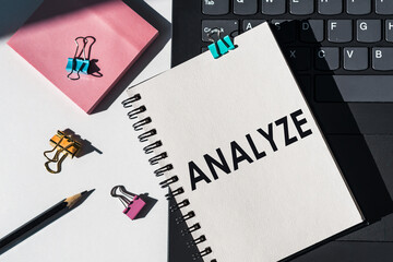 Notebook with tools and notes about ANALYZE lies on laptop.