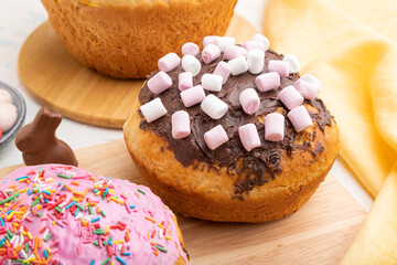 Homemade glazed and decorated easter pies with chocolate eggs and rabbits on a white concrete background. Side view, close up.