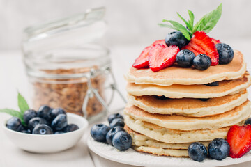 Classic american pancakes with fresh berry on white wood background. Summer homemade breakfast.