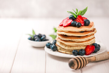 Classic american pancakes with fresh berry on white wood background. Summer homemade breakfast.