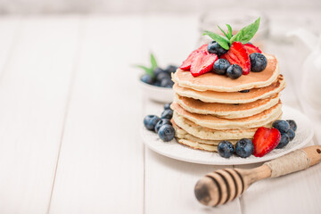 Classic american pancakes with fresh berry on white wood background. Summer homemade breakfast.