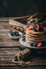 Fototapeta na wymiar American pancakes with fresh berry on wood background. Summer homemade breakfast.