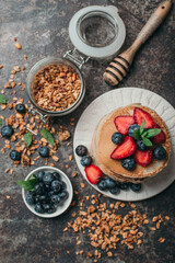 American pancakes with fresh berry and granola on metal background. Summer homemade breakfast.