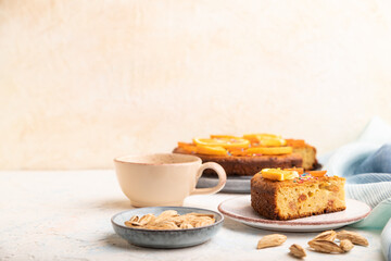 Fototapeta na wymiar Orange cake with almonds and a cup of coffee on a white concrete background. Top view, selective focus, copy space.