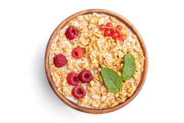 Wheat flakes porridge with milk, raspberry and currant in wooden bowl isolated on white background. Top view, close up.