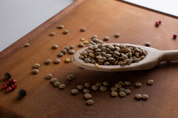 Lentils and spoon in a wooden spoon close up on an old table.