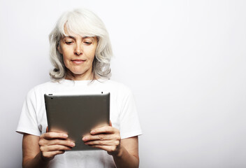 Lifestyle, tehnology and old people concept: Senior happy gray-haired woman using ipad on white background