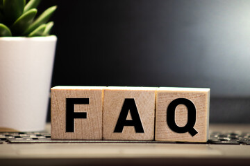 FAQ word on wooden block on top of wooden background.
