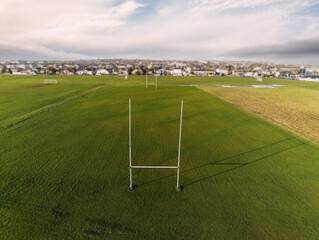 Irish National sport goal post on a green grass field, Selective focus, Galway city in the background. Hurling, rugby, camogie and gaelic football training. Warm sunny day.