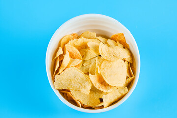 Bowl of crispy chips on blue background