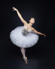 attractive ballerina poses gracefully in the studio on a black background © Vadzim
