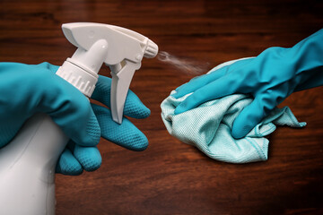 Hands in blue rubber gloves with a cleaning cloth and antibacterial sanitize spray bottle...