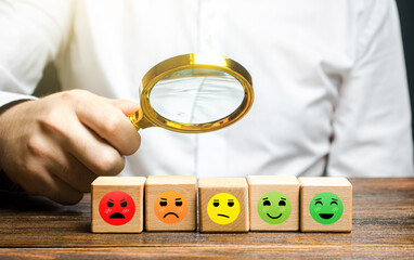 The man studies blocks with mood symbols from happily satisfied to angry unsatisfied. Concept of...