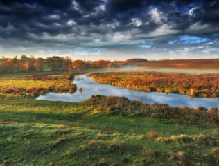 Fototapeta na wymiar picturesque clouds over the river. autumn sunrise in the meadow