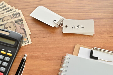 On the desk were Japanese yen bills, a calculator, a notebook, and a word book with the word ABL written on it. It was an abbreviation for the financial term Asset Based Lending.