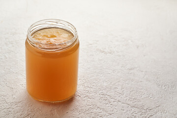 A jar of cooled down congealed beef bone broth on a bright background with copy space