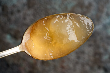 Chilled congealed beef bone broth on a metal spoon, top view