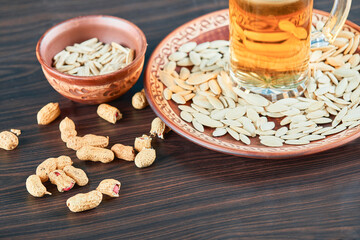 Sunflower seeds, peanuts and a glass of beer on wooden table