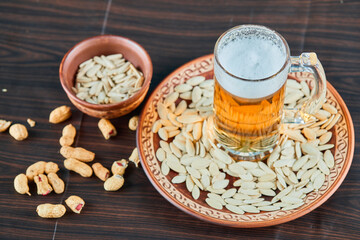 Sunflower seeds, peanuts and a glass of beer on wooden table