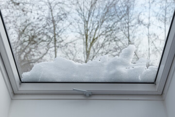 Selective focus and interior view through skylight with snow on glass in winter season. 