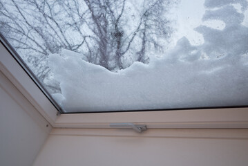 Selective focus and interior view through skylight with snow on glass in winter season. 