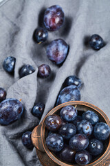 Garden plums in a bowl on gray tablecloth