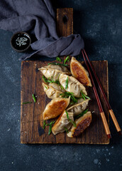 Asian dumplings Gyoza potstickers on old wooden board. Top view, copy space