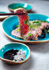 Beef tataki with sauce and sesame on blue plate. Japanese food