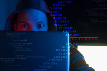 anonymous hacker in hoodie breaking computer system by scaning password on virtual screen, front...