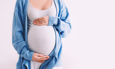 Beautiful pregnant woman hugging her belly in white background. Expectant mother waiting for baby...