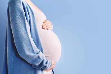 Beautiful pregnant woman hugging her belly in white background. Expectant mother waiting for baby...