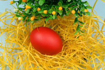Egg painted red on yellow straw, symbolizing Easter.