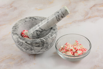 Crushing peppermint candy into pieces in mortar and pestle for baking ingredient