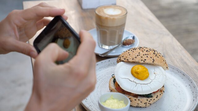 Food blogger taking pictures of vegan burger with plant based egg on top to share on social media 
