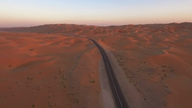 Liwa oasis long curved sandy desert road along Moreeb dune Abu Dhabi extreme terrain aerial view forward descent